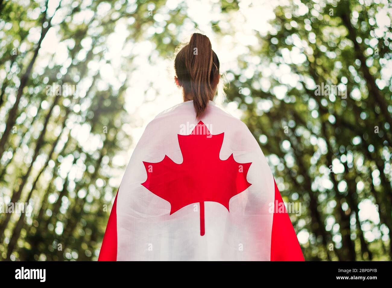 Child teenager girl at nature background an Canada flag on her shoulders Stock Photo