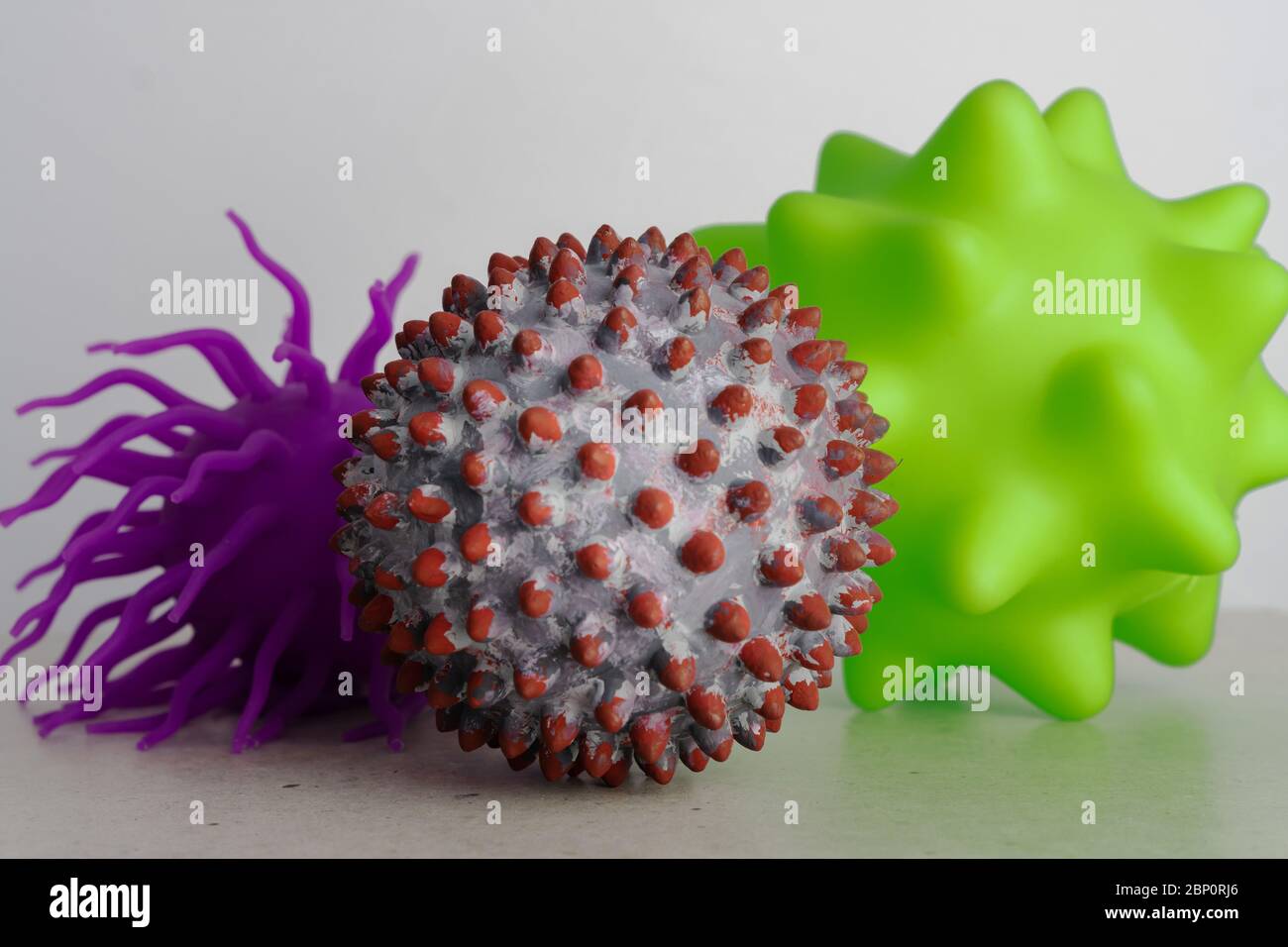 Two ball toys as a representation of virus or bacterias and one as a symbol of a SARS-CoV-2 virion Stock Photo