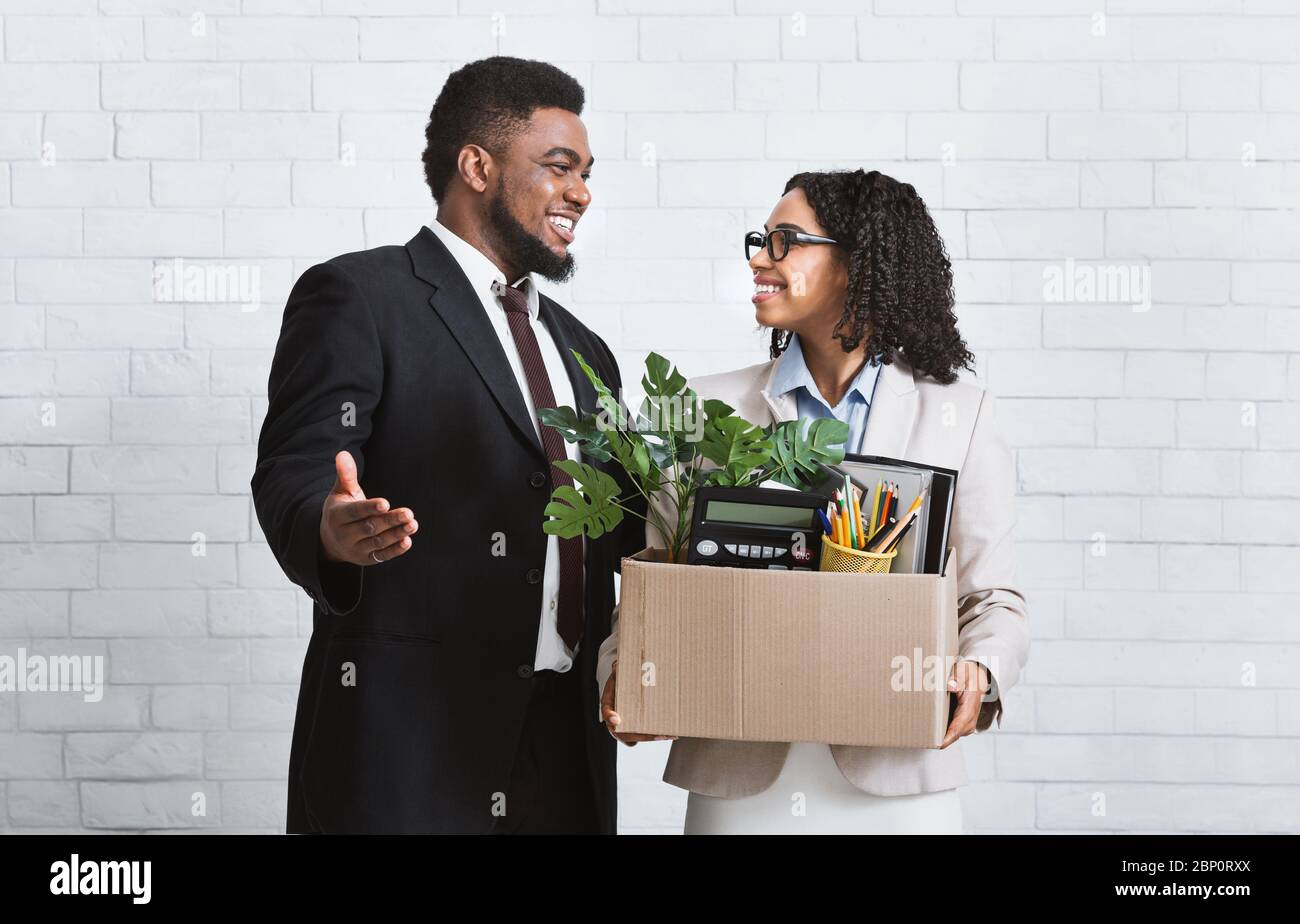 Smiling young woman with box of personal things being hired to work in business company, meeting her new boss Stock Photo