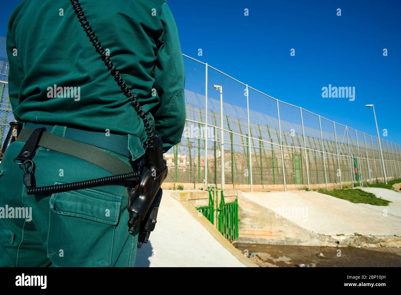 MELILLA,SPAIN-APRIL 19 : A Guardia Civil stands near the perimeter fence that separates the Spanish enclave of Melilla and Morocco on April 19,2010 in Melilla, Spain. The fence which marks the border around the Spanish enclave in northern Morocco was build to discourage illegal immigrants from attempting to enter to Melilla. ( Photo by Jordi Cami) Stock Photo
