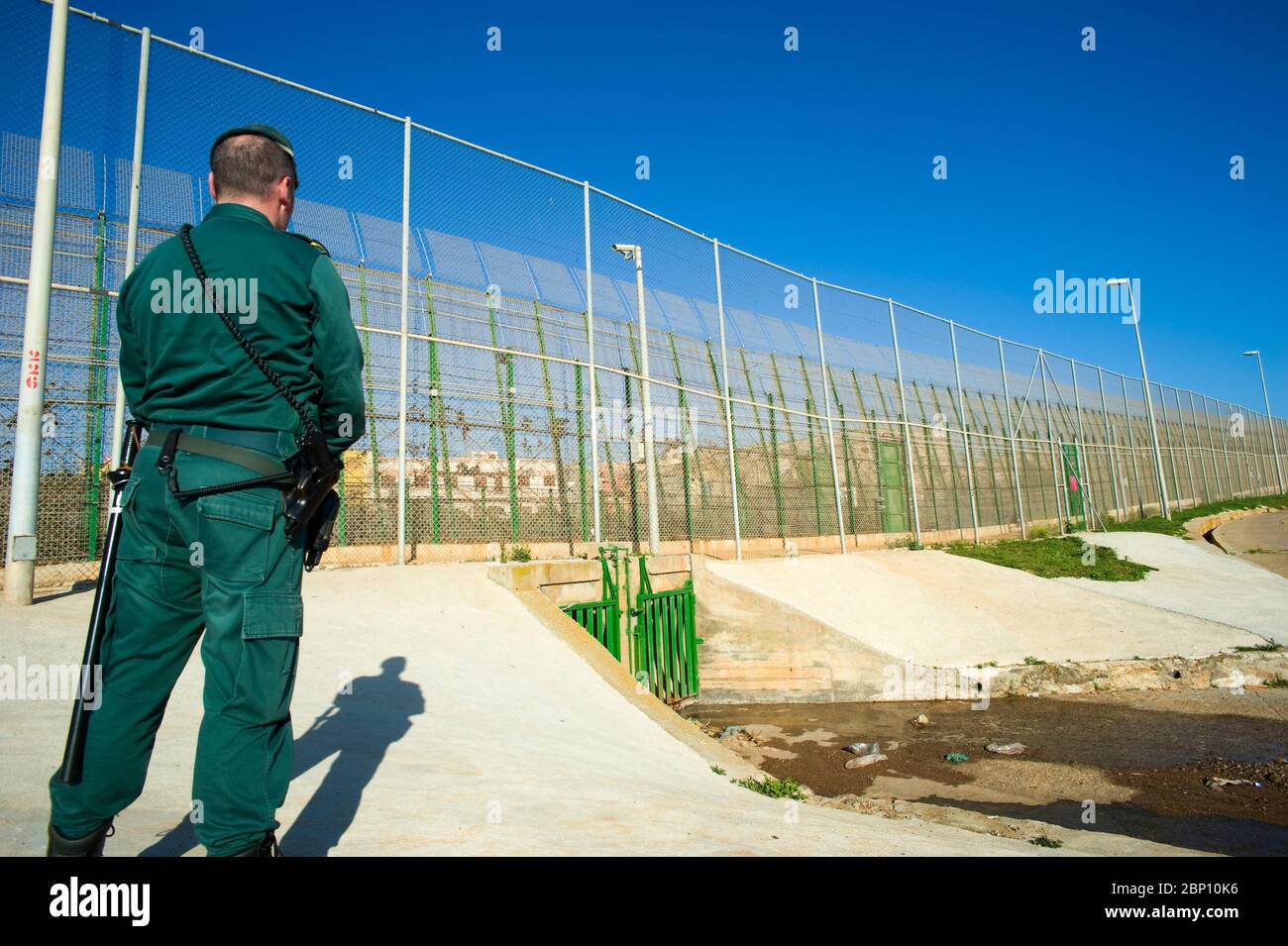 MELILLA,SPAIN-APRIL 19 : A Guardia Civil stands near the perimeter fence that separates the Spanish enclave of Melilla and Morocco on April 19,2010 in Melilla, Spain. The fence which marks the border around the Spanish enclave in northern Morocco was build to discourage illegal immigrants from attempting to enter to Melilla. ( Photo by Jordi Cami) Stock Photo