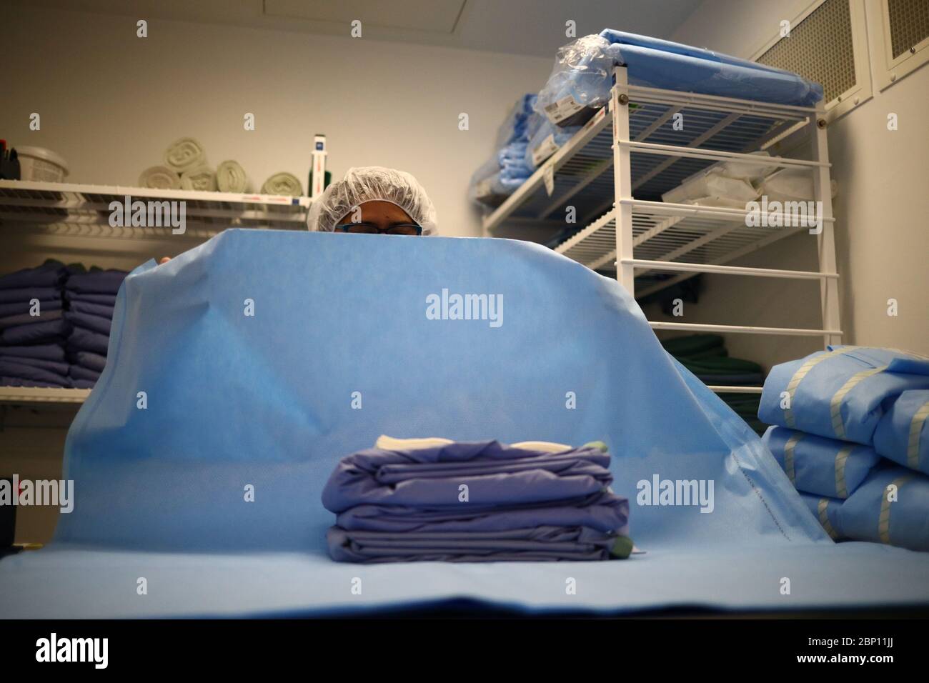 Laundry worker prepares clean reusable gowns hires stock photography
