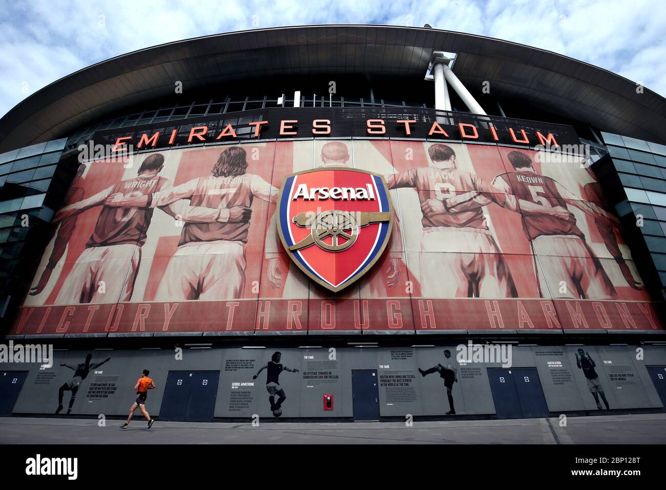 A lone jogger runs past the Emirates Stadium, home of Arsenal, today should have seen Arsenal take on Watford in what would have been their final Premier League game of the 19/20 season. Stock Photo