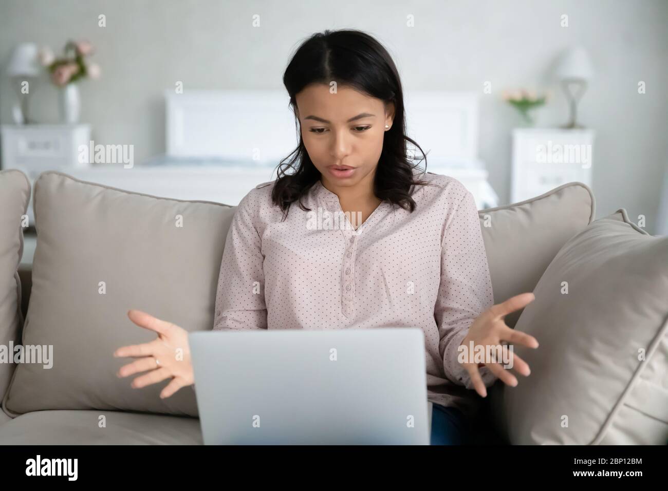 Woman having problems with computer looks at screen feels annoyed Stock Photo