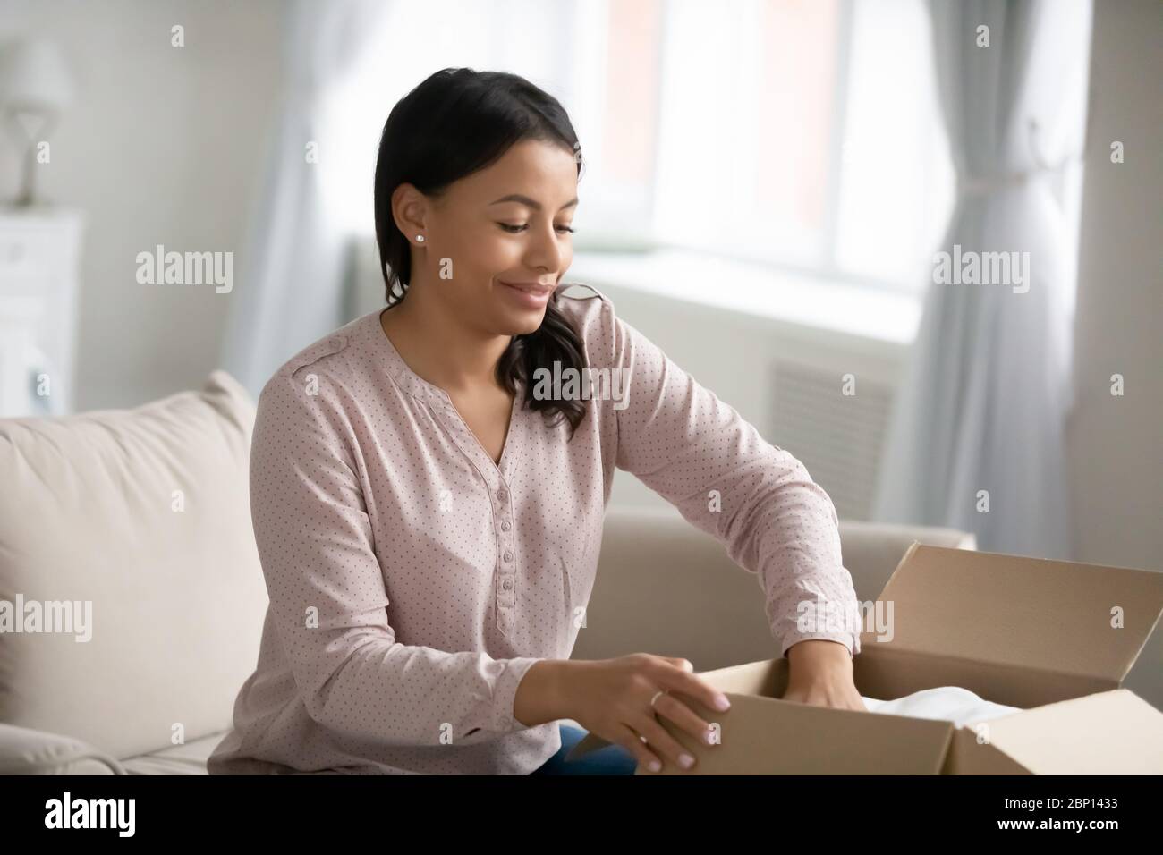 African woman put clothes in donation box participates in charity Stock Photo