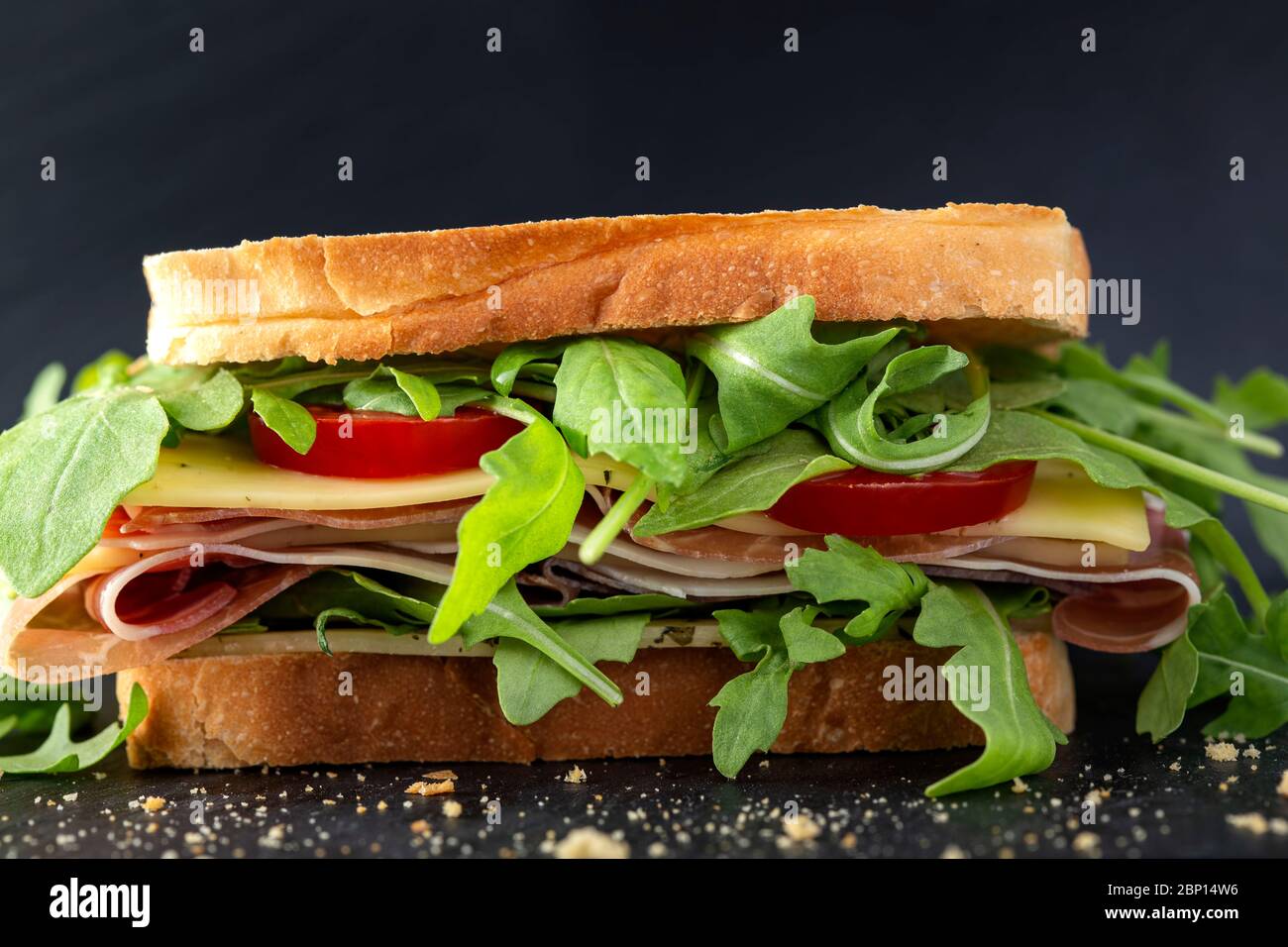 Sandwich with prosciutto, cheese with nettles, tomatoes and a lot of aragula Stock Photo