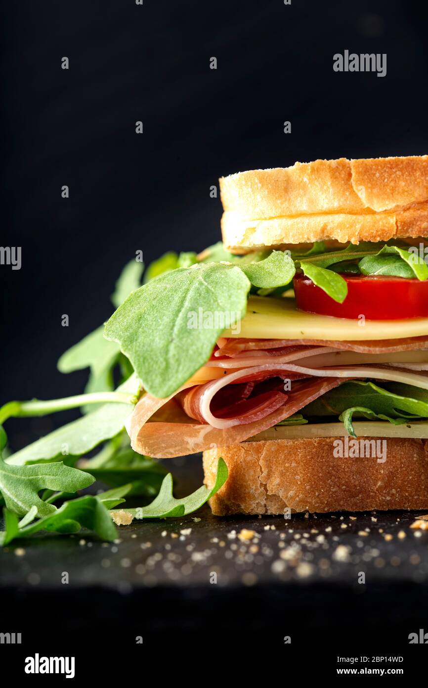 Sandwich with prosciutto, cheese with nettles, tomatoes and a lot of aragula Stock Photo