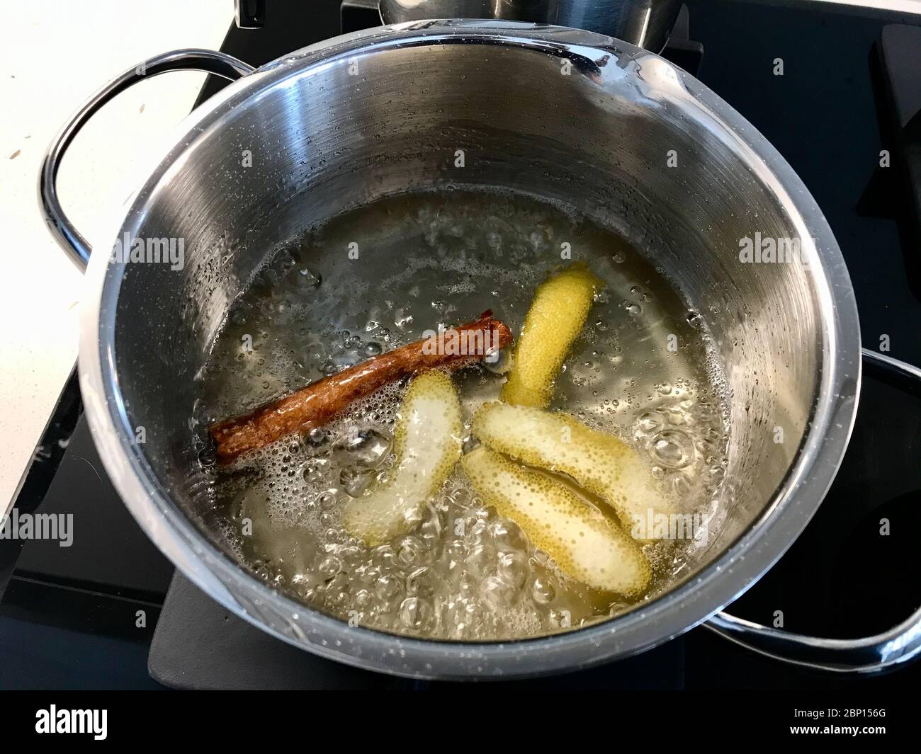 Making Sherbet with Cinnamon Stick, Lemon Peel and Water in Pot for Pasteis de Nata or Belem Tart. Portuguese Custard made with Egg, Cinnamon, Sugar a Stock Photo