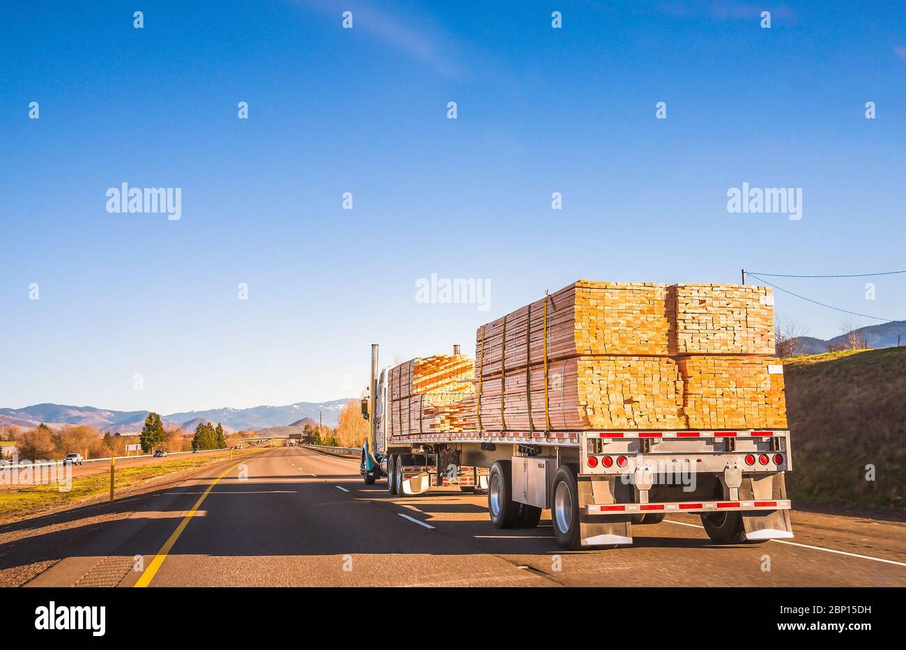 truck with wood on freeway at sunset. Stock Photo