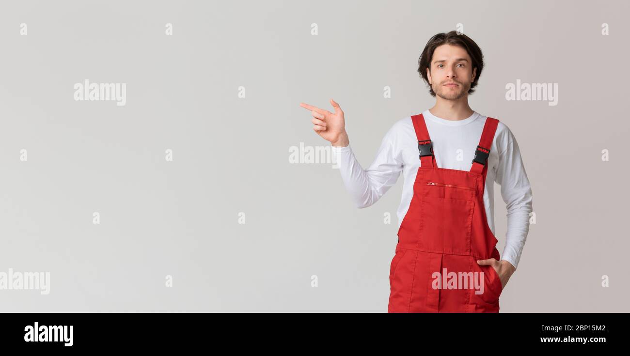 Young confident workman in uniform pointing aside at copy space Stock Photo