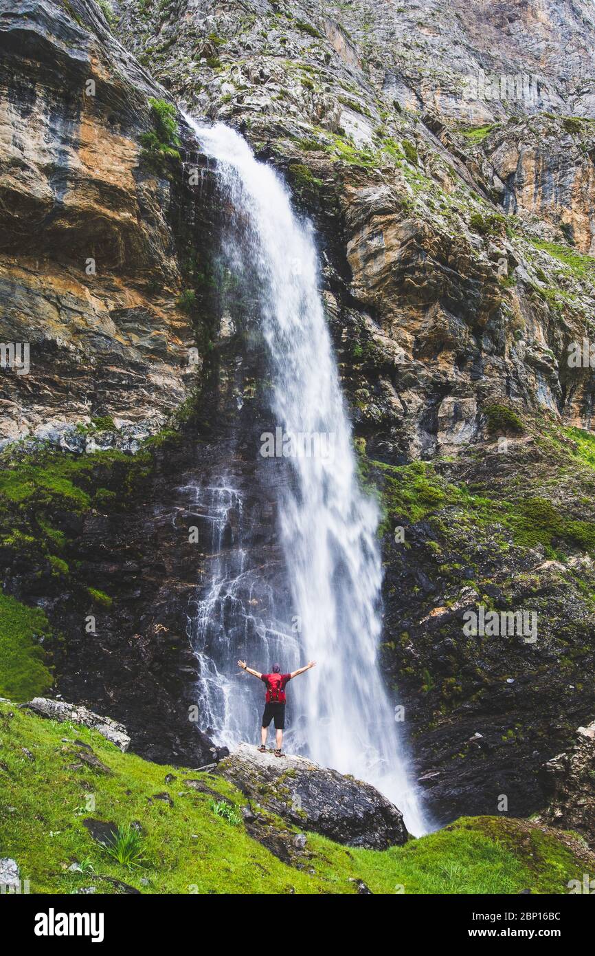 Man under a spectacular waterfall in the mountains Stock Photo
