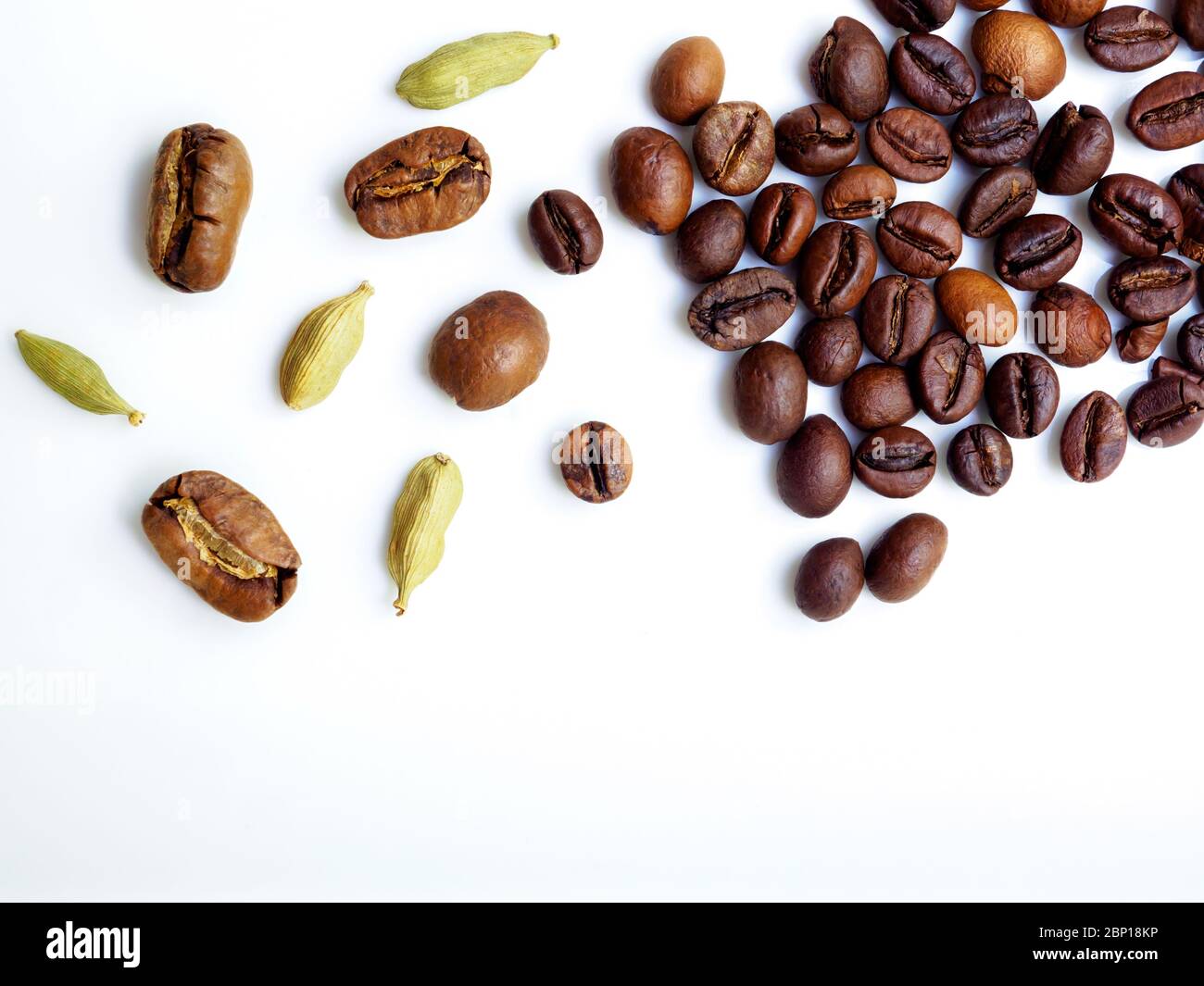 Flat lay. Coffee beans and cardamom grains are scattered on a white ...