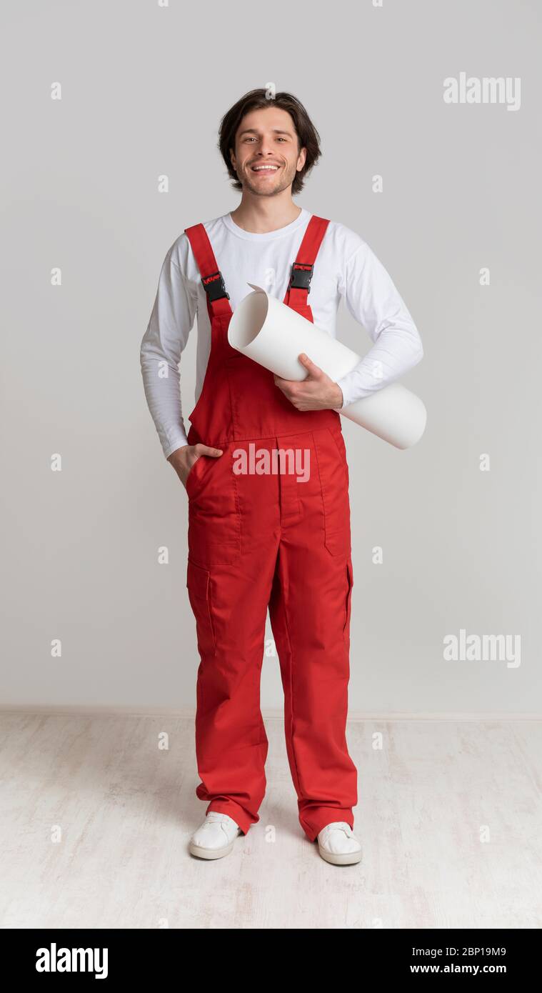 Smiling construction worker holding project plan in hands and posing to camera Stock Photo