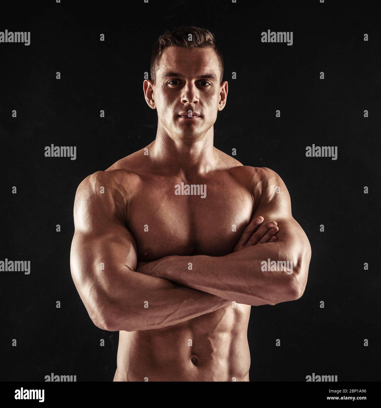 Fitness in gym, sport and healthy lifestyle concept. Handsome athletic man showing his trained body on dark background. Bodybuilder male model Stock Photo