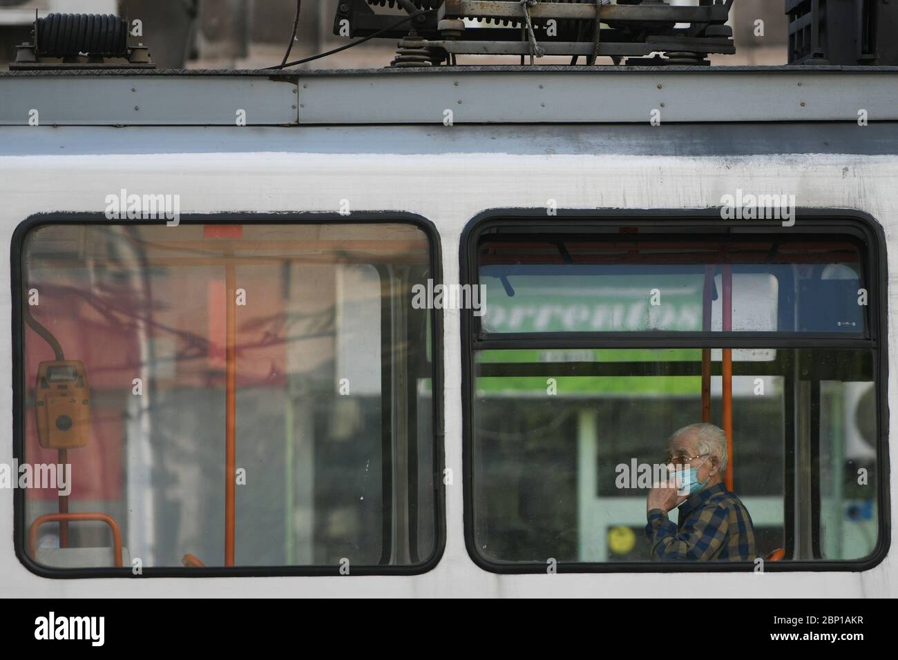 An elderly person improperly wears a protective mask, in a tram, in Bucharest, Saturday, May 16, 2020 Stock Photo