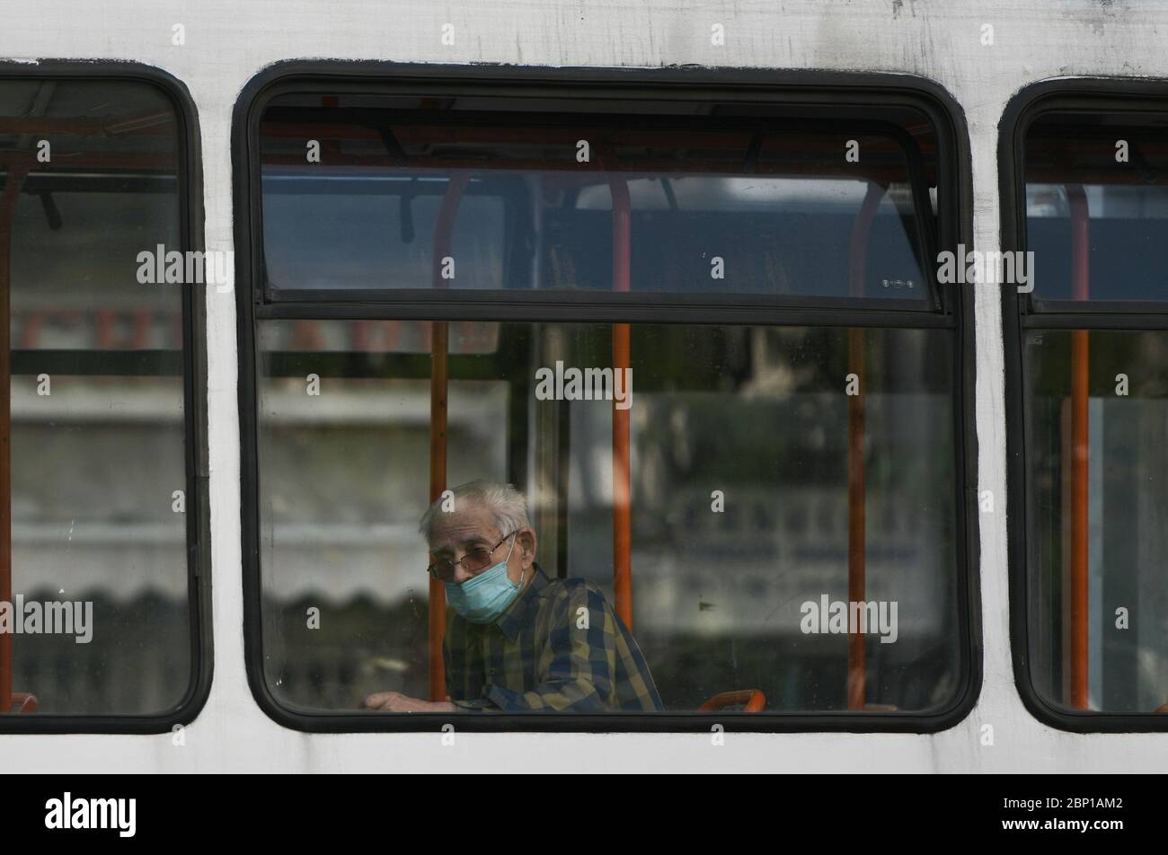 An elderly person improperly wears a protective mask, in a tram, in Bucharest, Saturday, May 16, 2020 Stock Photo