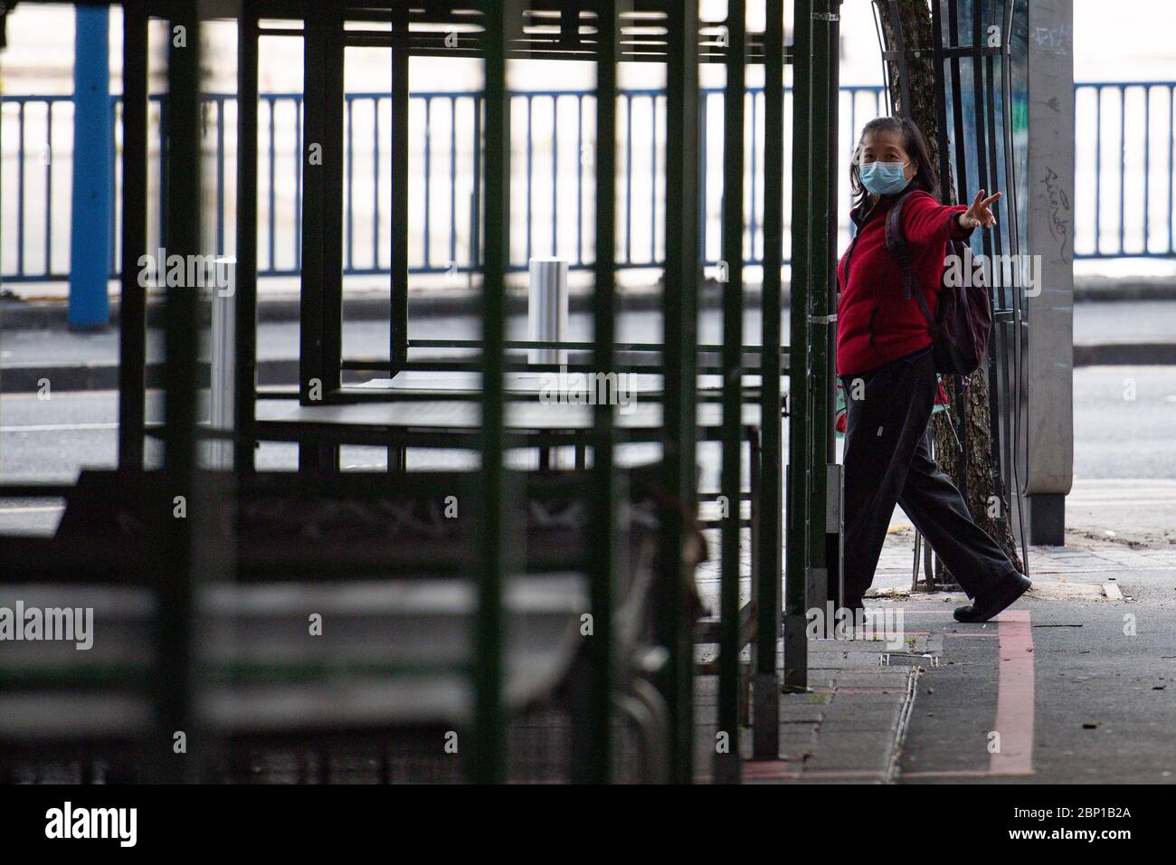 A lady wearing a protective face mask displays a peace hand-gesture whilst passing the deserted Bullring Open Market in Birmingham, after the introduction of measures to bring the country out of lockdown. Stock Photo