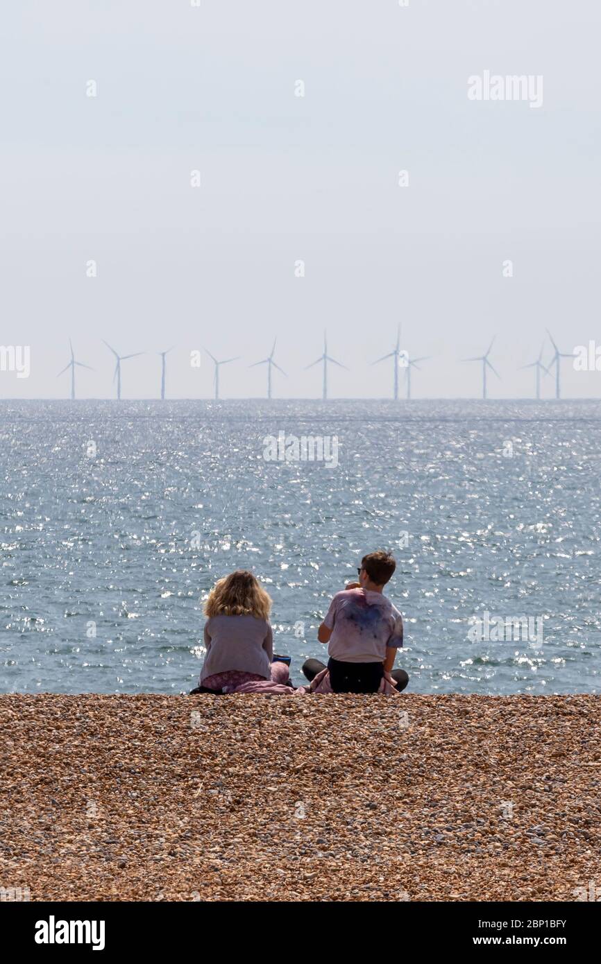 couple sitting on beach with wind farm Stock Photo