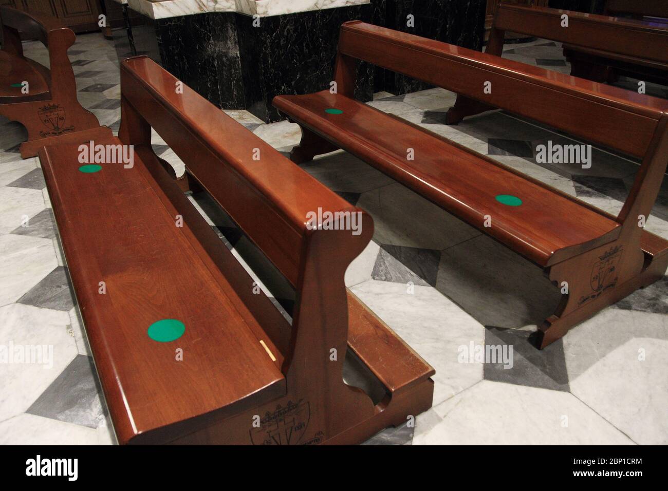 The signs placed on the benches of the church where the faithful can sit during the Eucharistic celebrations to maintain social distancing . Stock Photo