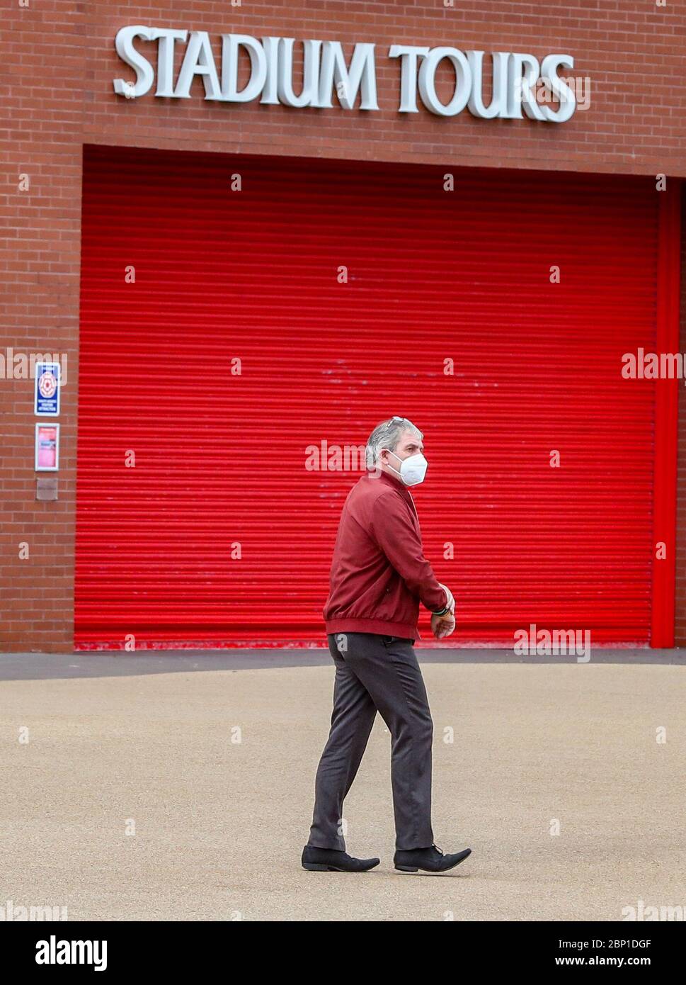 A man wearing a face mask (covering) walks past Anfield - Home of Premiership table toppers Liverpool. Today, Liverpool should have played their final match of the 19/20 away to Newcastle at St James Park. Stock Photo