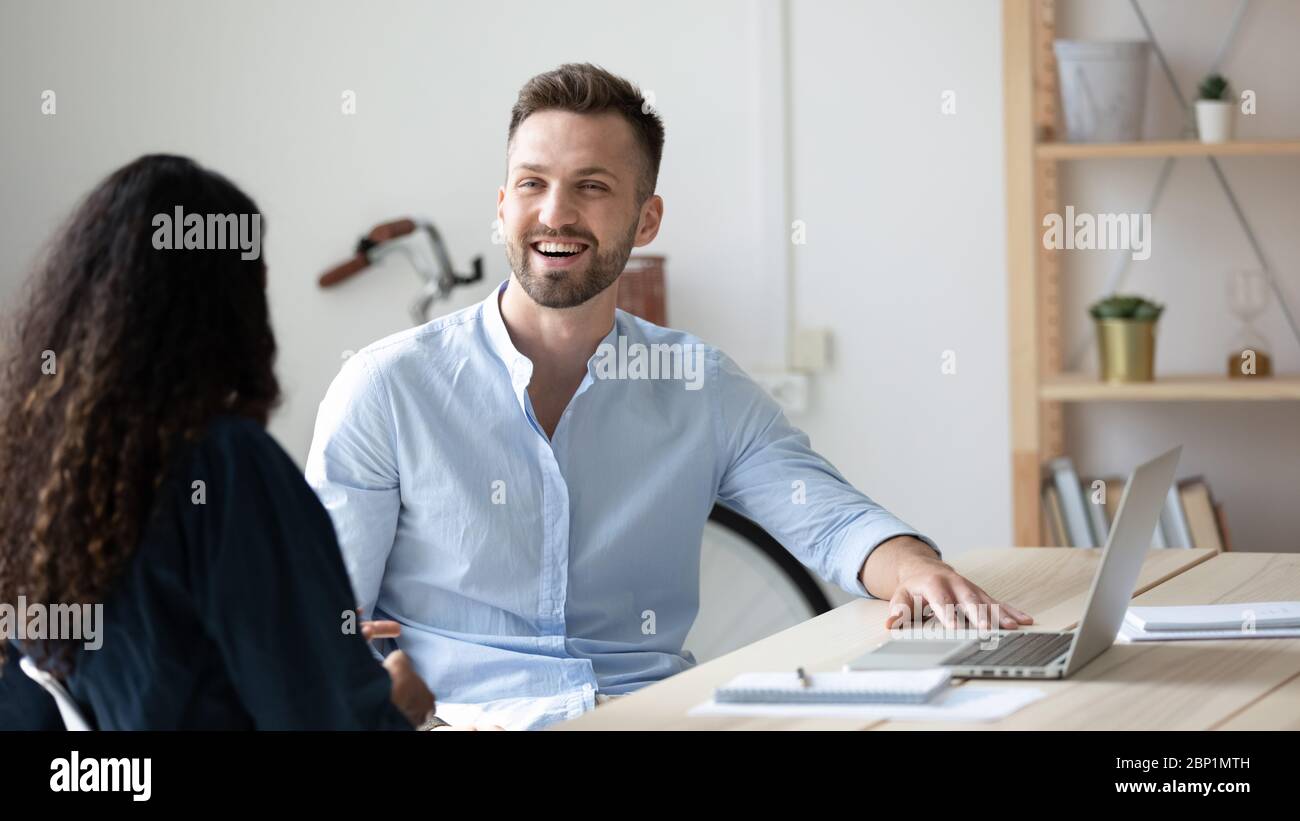 Laughing businessman talking with businesswoman using laptop in boardroom. Stock Photo