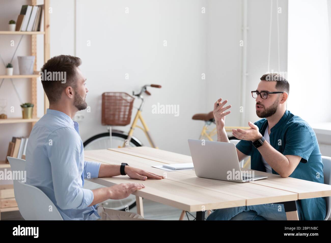 Serious bearded businessman talking and interviews new male applicant. Stock Photo