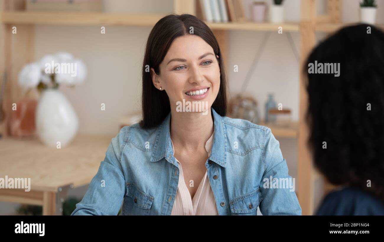 Close up smiling attractive young businesswoman listening new applicant introduction. Stock Photo