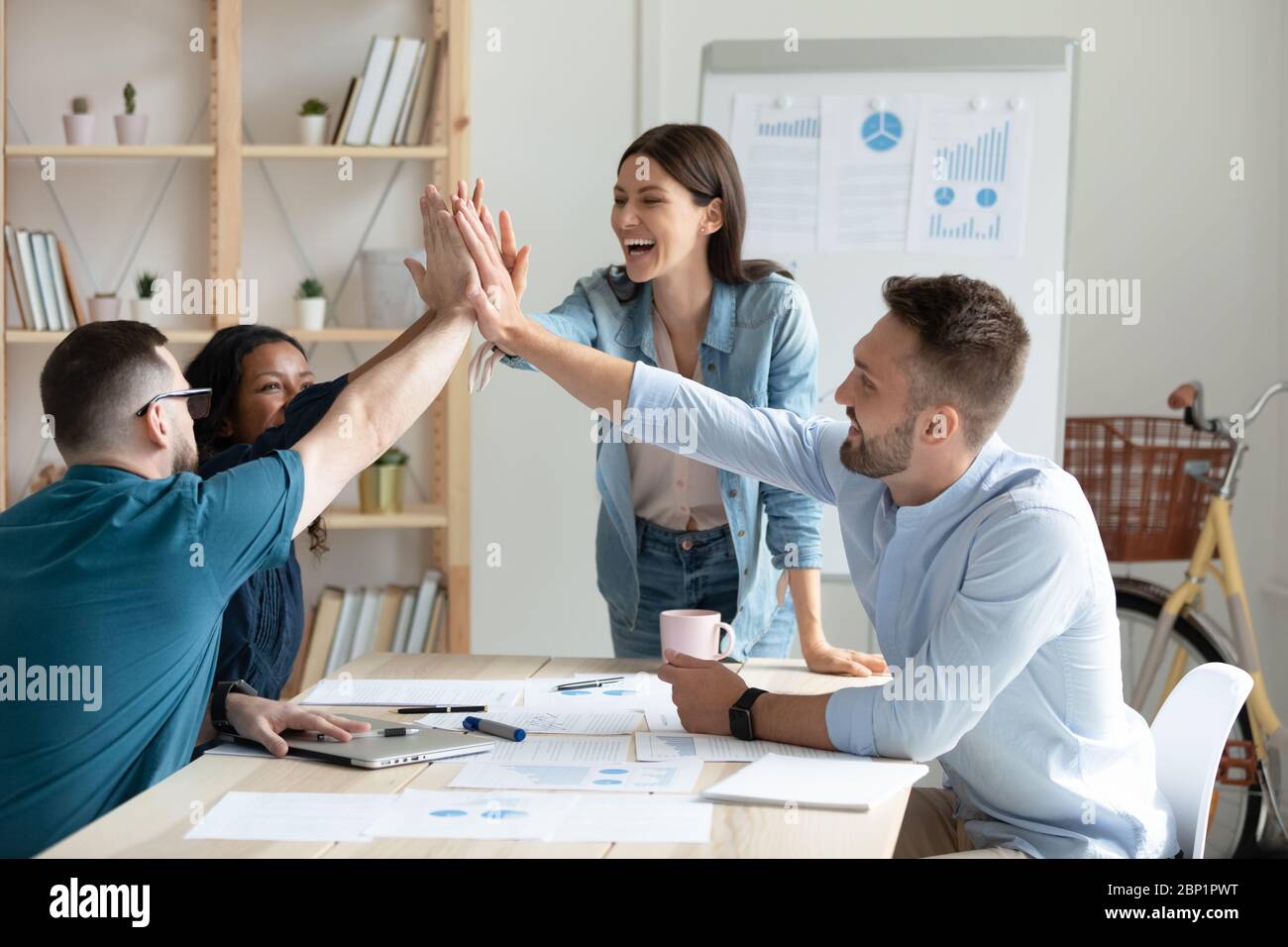 Diverse workers with female mentor, coach giving high five Stock Photo ...