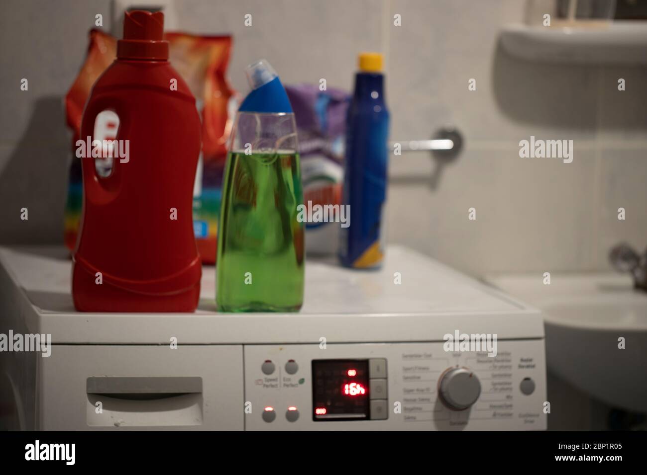 Washing machine in the bathroom. Plastic detergent box and sachets on