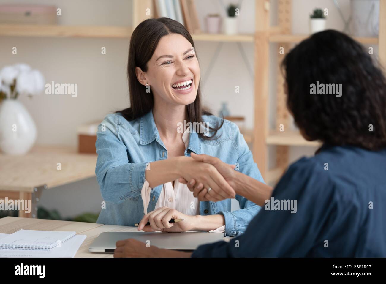 Close up smiling young businesswoman shaking hands with job seeker. Stock Photo