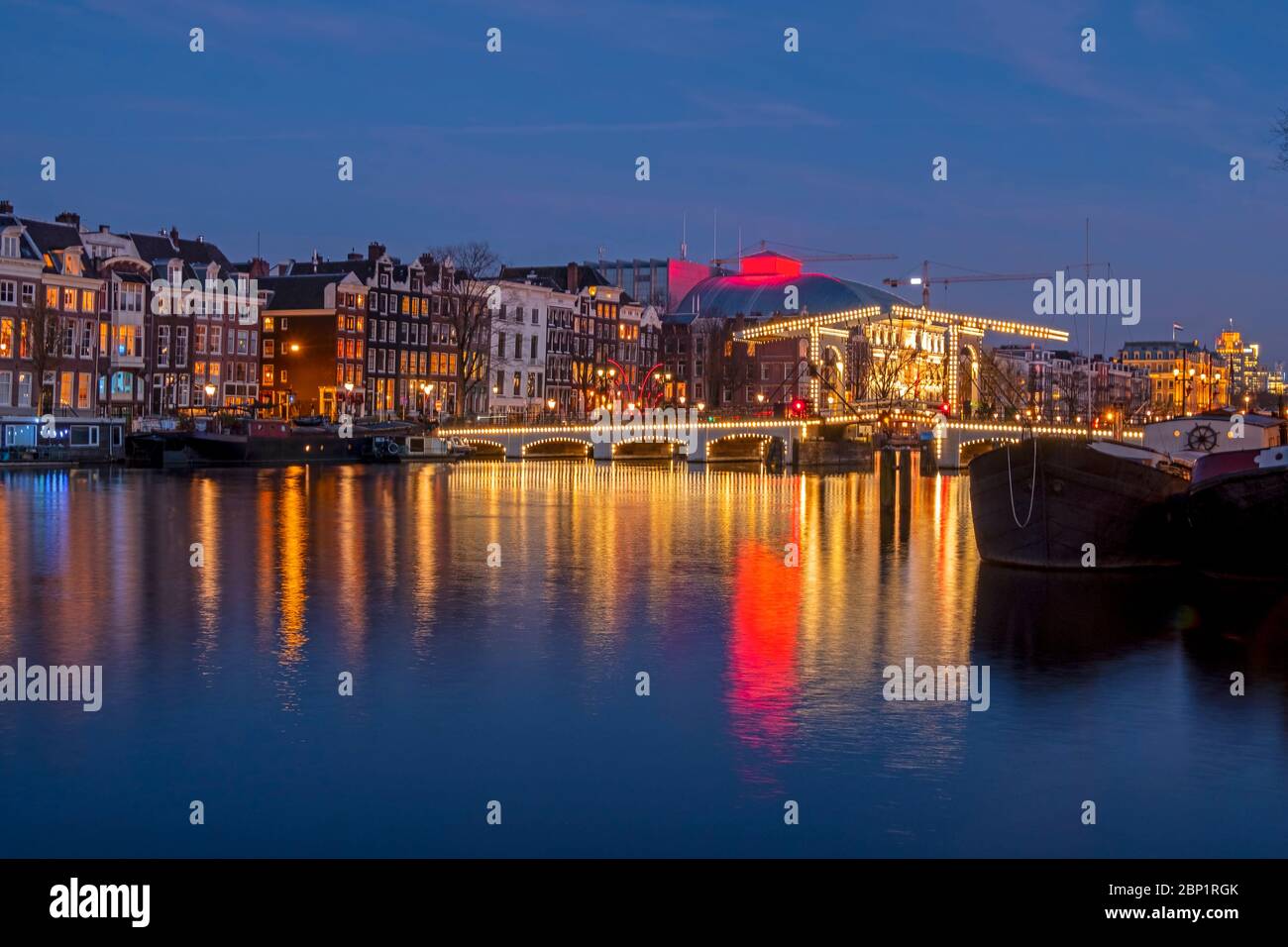 City scenic from Amsterdam at the river Amstel with the Tiny bridge in the Netherlands at night Stock Photo