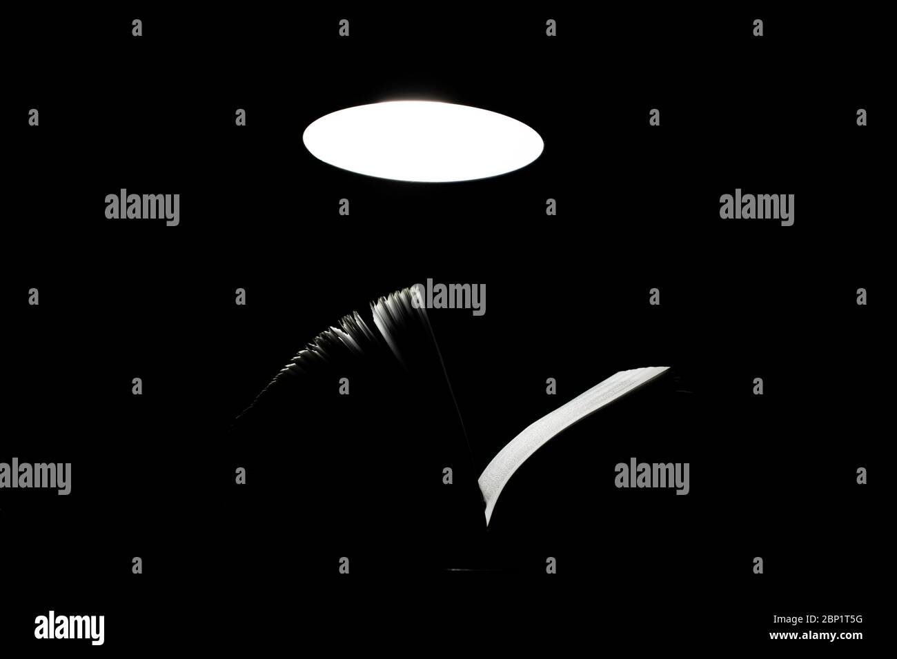 Open book on a table lamp in the dark Stock Photo