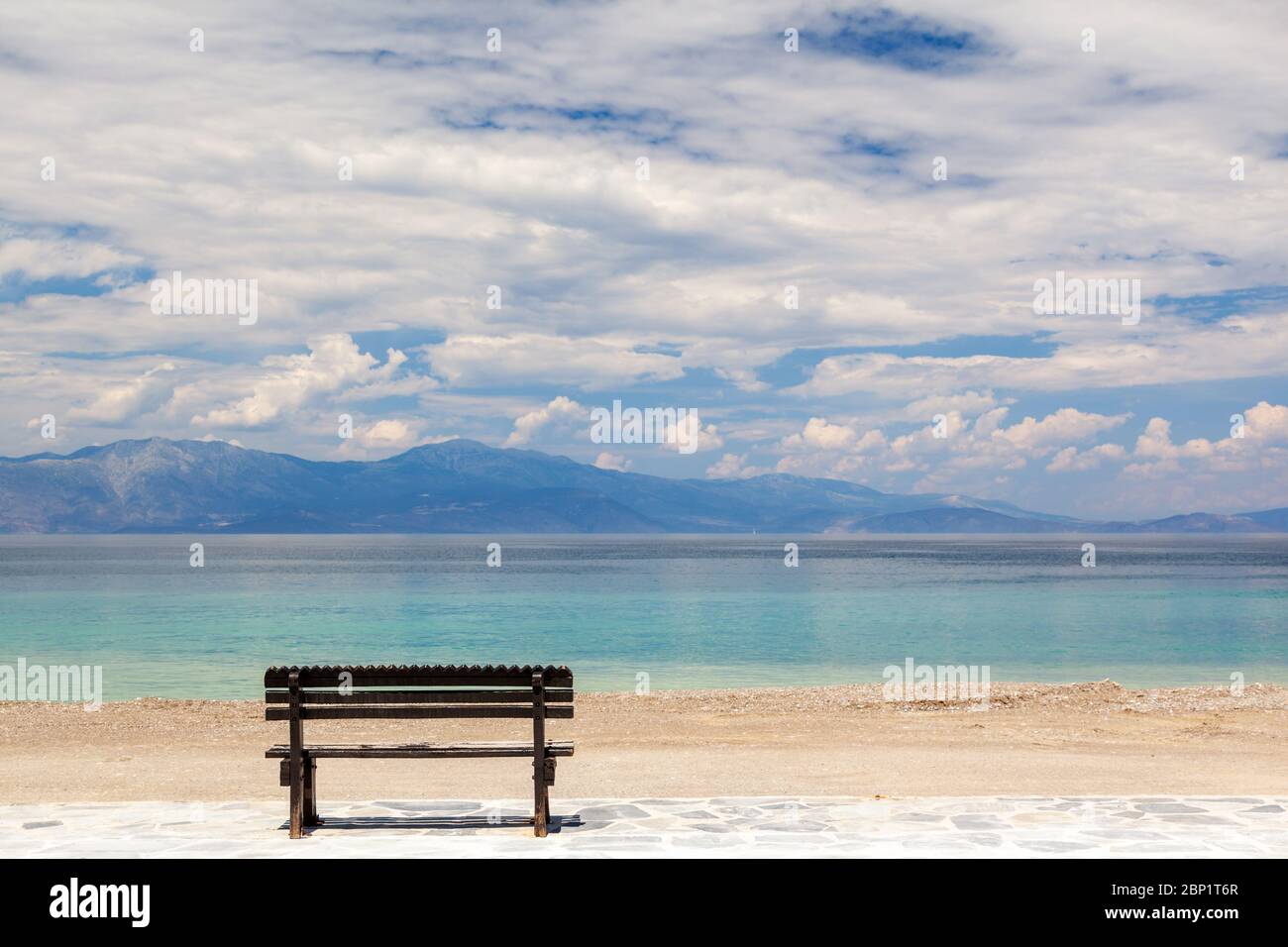 Empty wooden bench by the sea in a cloudy day, gazing the Corinthian gulf, near Xylokastro town, in Peloponnese, Greece. Stock Photo