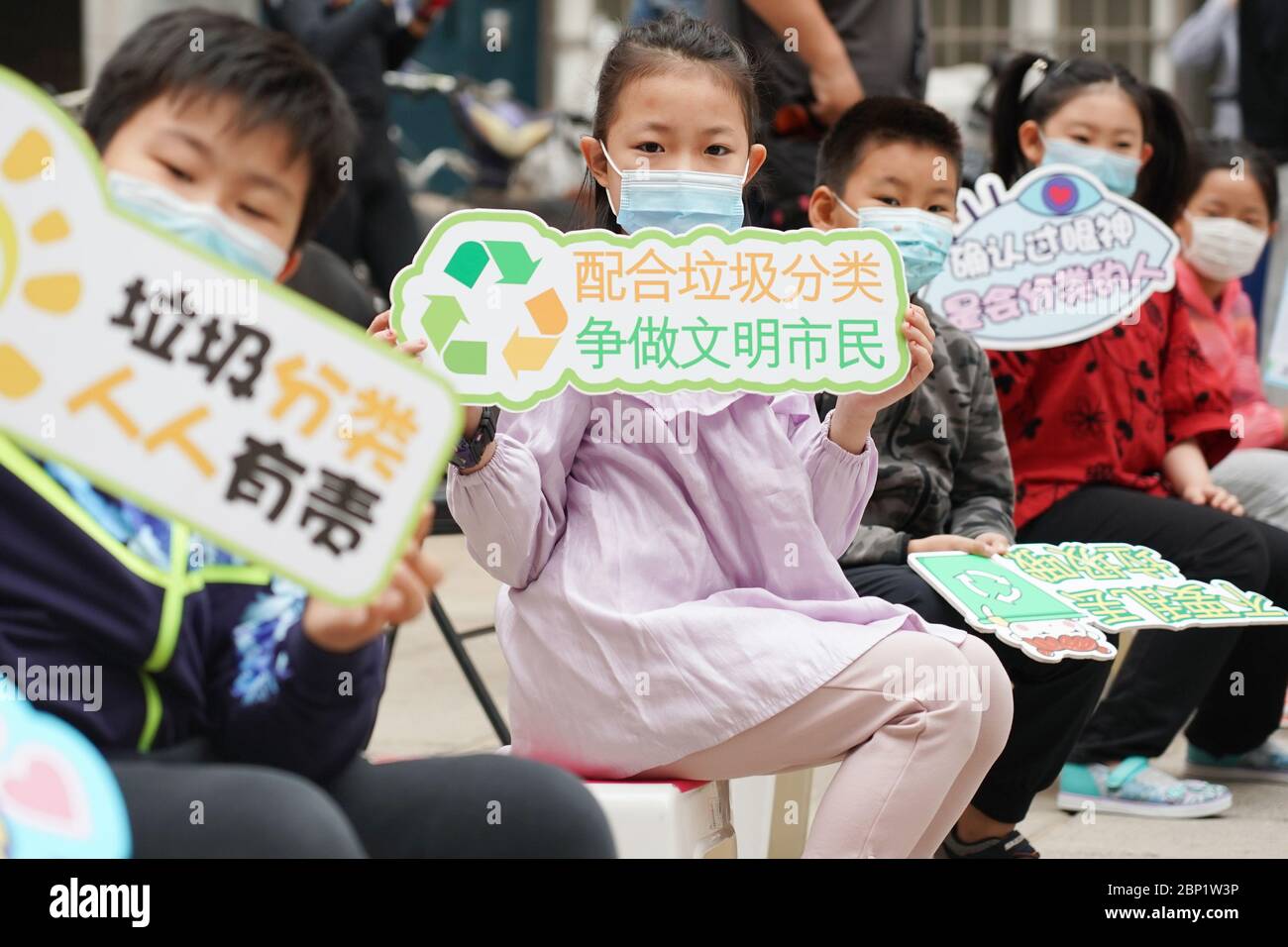 Beijing, China. 17th May, 2020. Young volunteers display placards showing  garbage sorting slogans at the Shaojiu residential community in Dongcheng  District of Beijing, capital of China, May 17, 2020. The Shaojiu community
