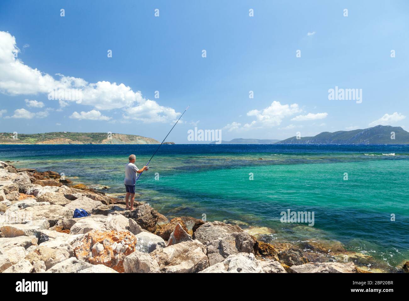Man fishing by the port of Methoni town, in Messinia region, Peloponnese, Greece, Stock Photo