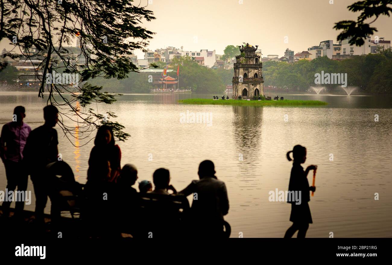 Unrecognisable people, the Hoan Kiem Lake and the turtle tower, taken at dusk, Hanoi, Vietnam Stock Photo
