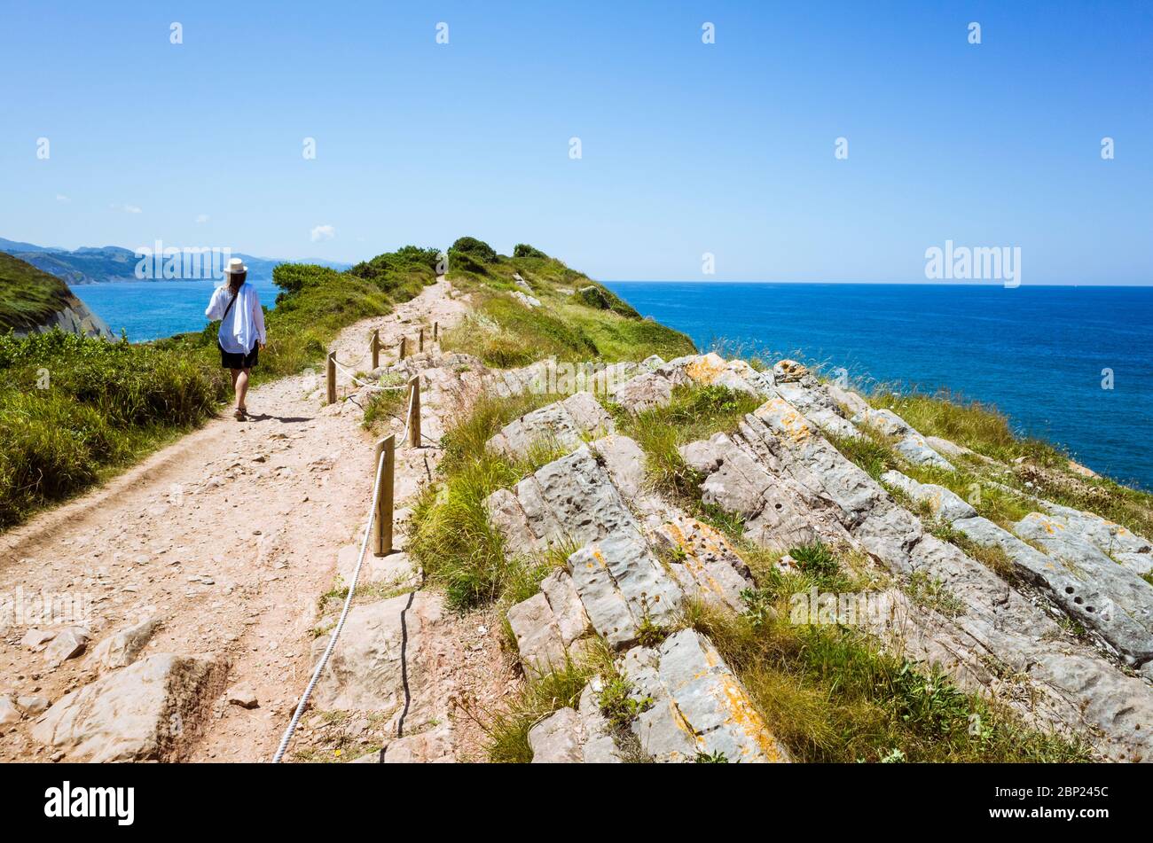 Zumaia, Gipuzkoa, Basque Country, Spain - July 15th, 2019 : A woman walks along the cliff made of flysch rock. Stock Photo