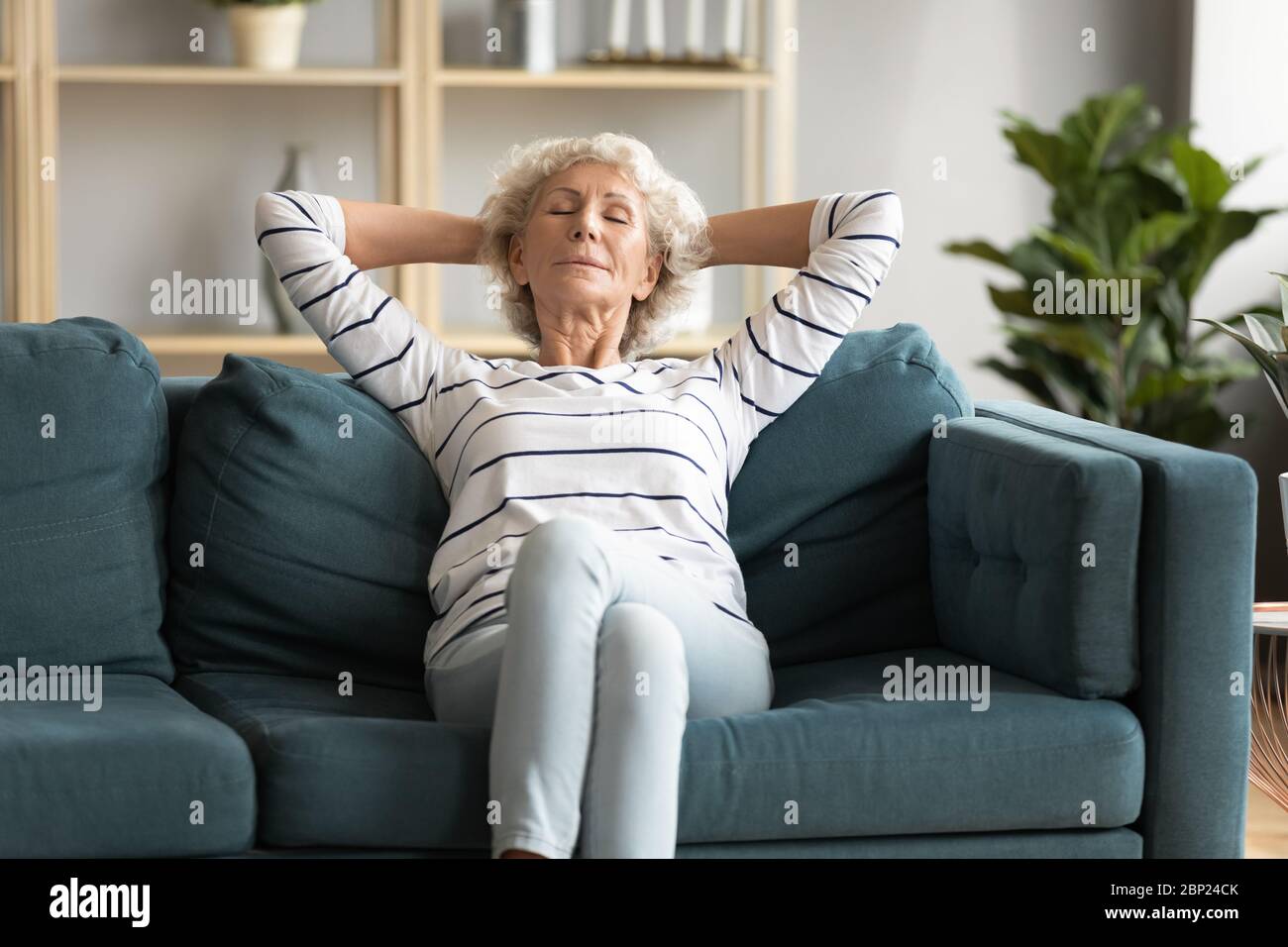 Peaceful serene mature senior lady napping alone on comfortable couch