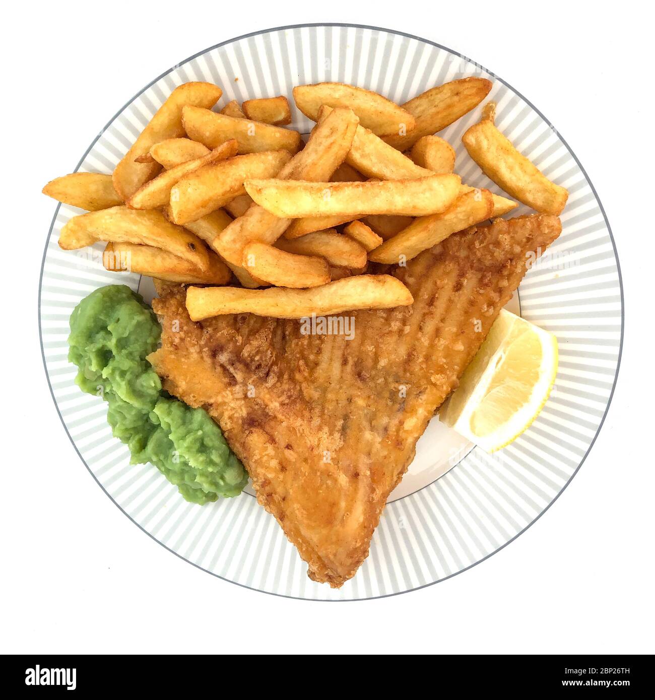 British fish and chips, in this case the fish is fried skate, chips, mushy peas and a slice of lemon. Stock Photo