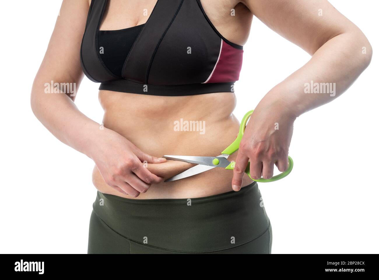 Middle-aged woman with obesity and saggy skin of the abdomen, on a white background, close-up. Scissors as a symbol of surgical retraction. Stock Photo