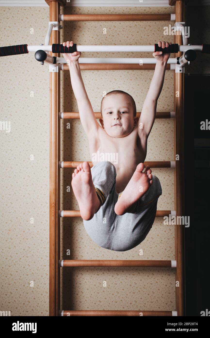 Home workout. The boy raises his legs in the hang Stock Photo - Alamy