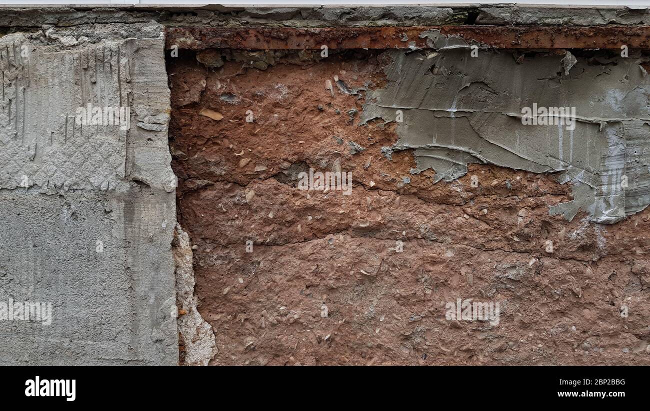 Rough layer of grey cement on brown textured wall surface closeup