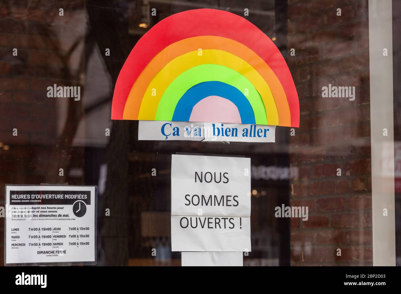 Montreal, CA - 16 May 2020: Ca va bien aller (Its going to be ok) message and Ouvert / Open sign on the door of a store during the Covid 19 pandemy Stock Photo
