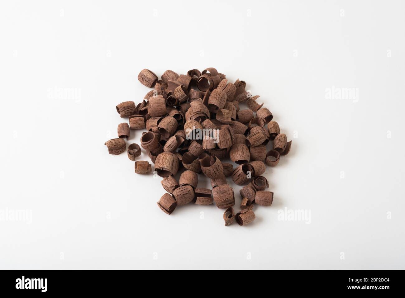 A collection of walnut wood shavings from carving, photographed against a plain, white