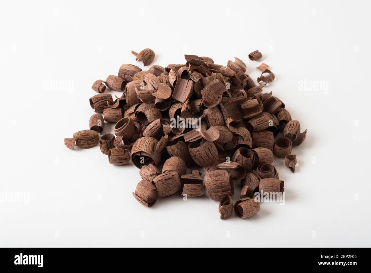 A collection of walnut wood shavings from carving, photographed against a plain, white