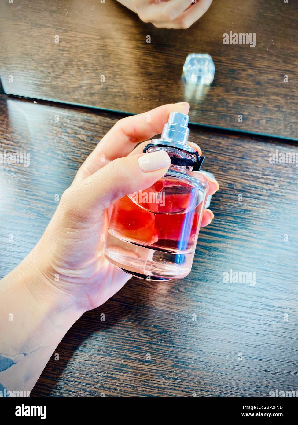A hand holding a plastic water bottle on a table Stock Photo