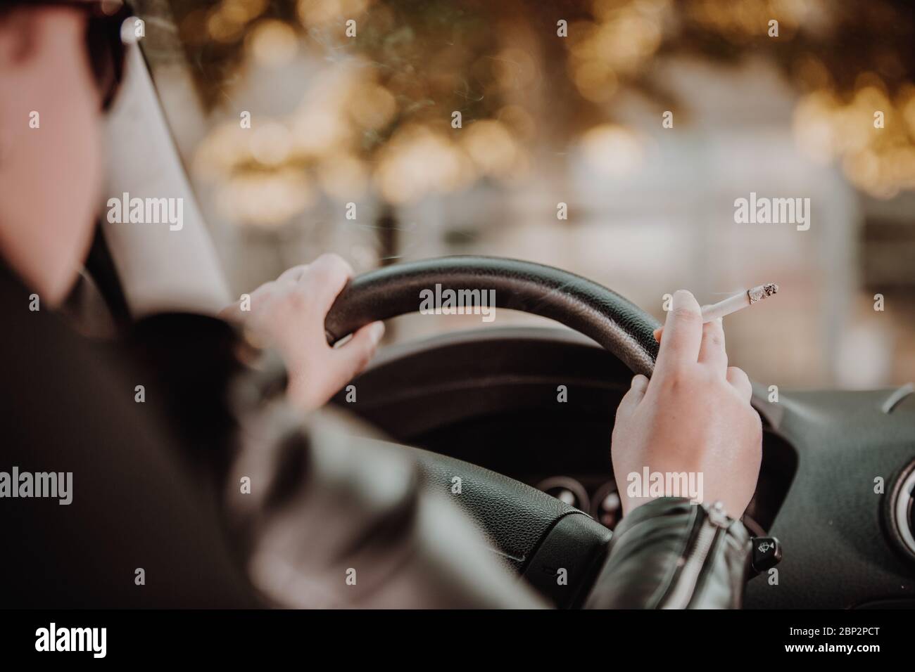 Close up of woman hand smoking cigarette inside the car while driving a