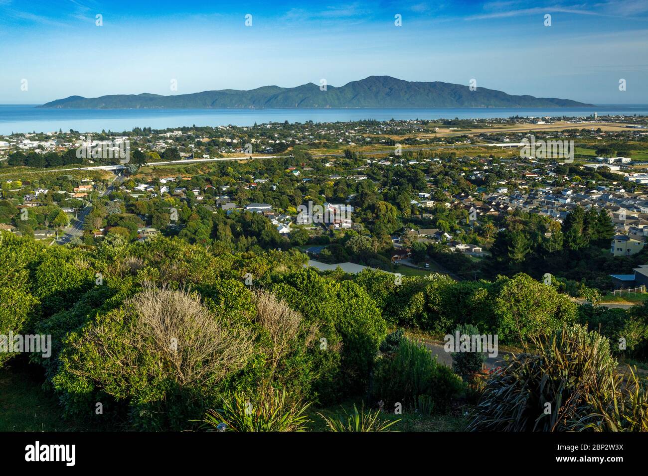 The view over Paraparaumu towards Kapiti Island, New Zealand. Strewn with driftwood. The island is a carefully managed bird and wildlife sanctuary. Stock Photo