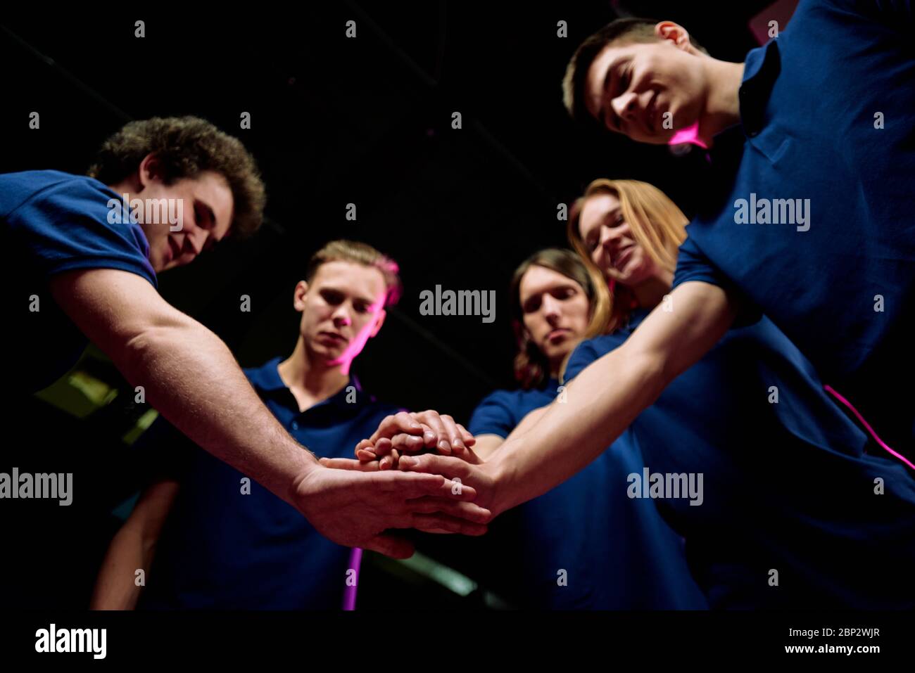 Team of five successful young esports clubbers making pile of hands