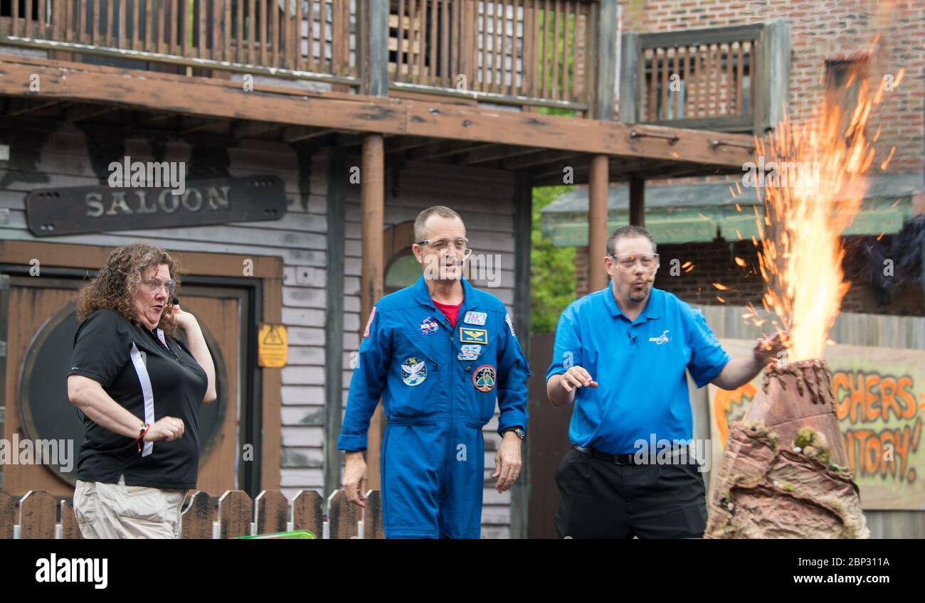 Astronaut Ricky Arnold at Six Flags America  NASA astronaut Ricky Arnold, center, and Smithsonian National Air and Space Museum's Beth Wilson, left, and Marty Kelsey, right, jump backwards as a model volcano erupts with fire during a Stem in 30 segment, Friday, May 3, 2019 at Six Flags America theme park in Upper Marlboro, MD. During Expedition 55/56, Arnold completed three spacewalks for a total of 19.5 hours outside the space station, and concluded his 197 day mission when he landed in a remote area near the town of Zhezkazgan, Kazakhstan in Oct. 2018. He also flew to the space station on sh Stock Photo
